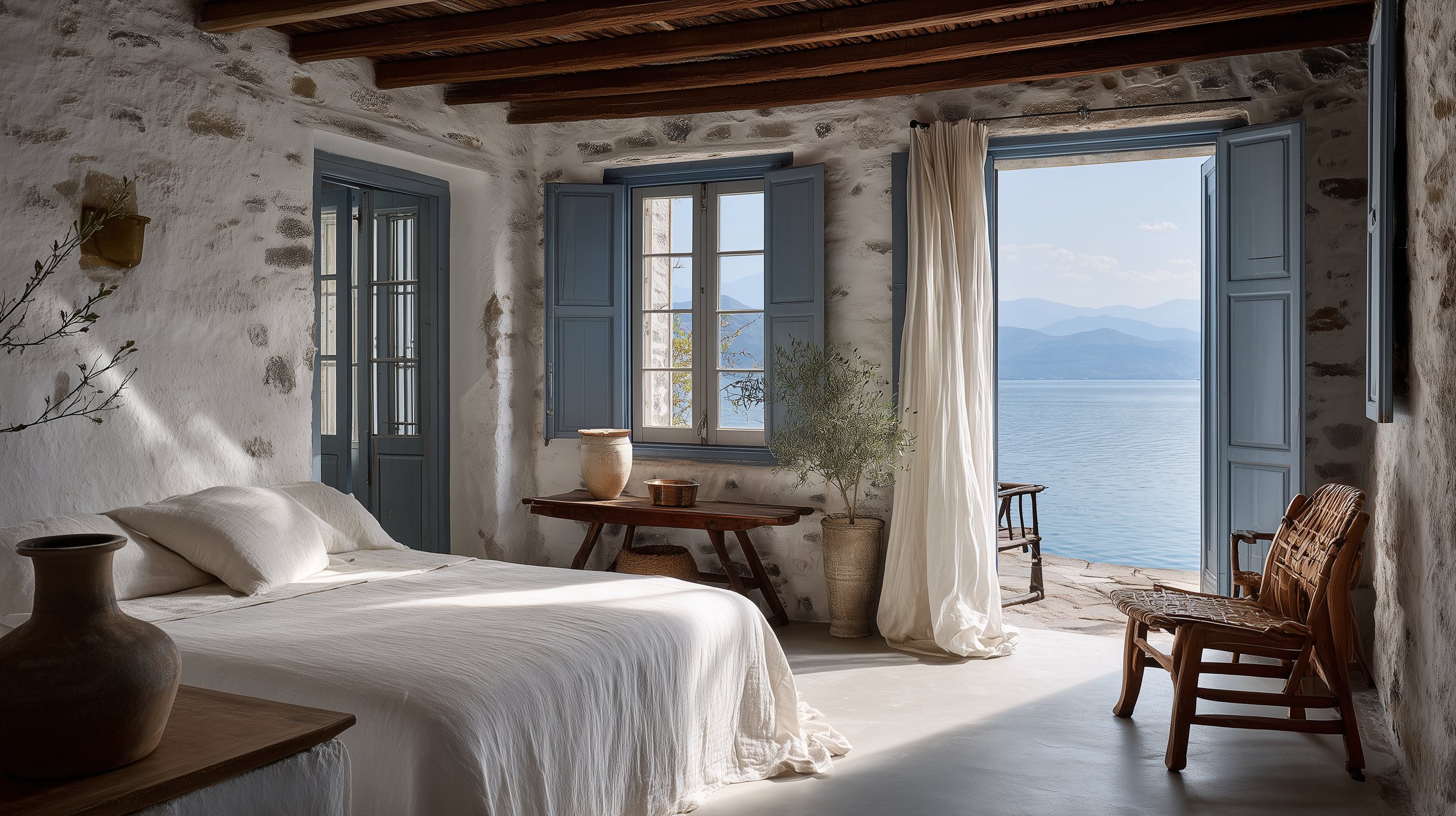 Whitewashed guest room with crisp white linen and blue shutters open onto the harbour