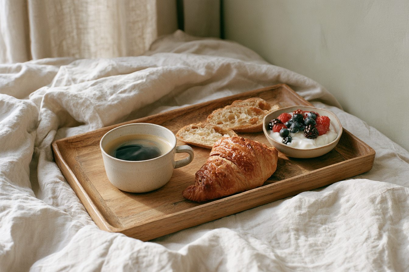 Breakfast tray with coffee, a croissant and berries on rumpled linen